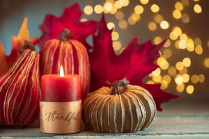 Thanksgiving decoration with pumpkins and greeting card on illuminated background and a rustic wooden table