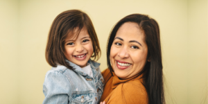 A mom holding her daughter and smiling for the picture