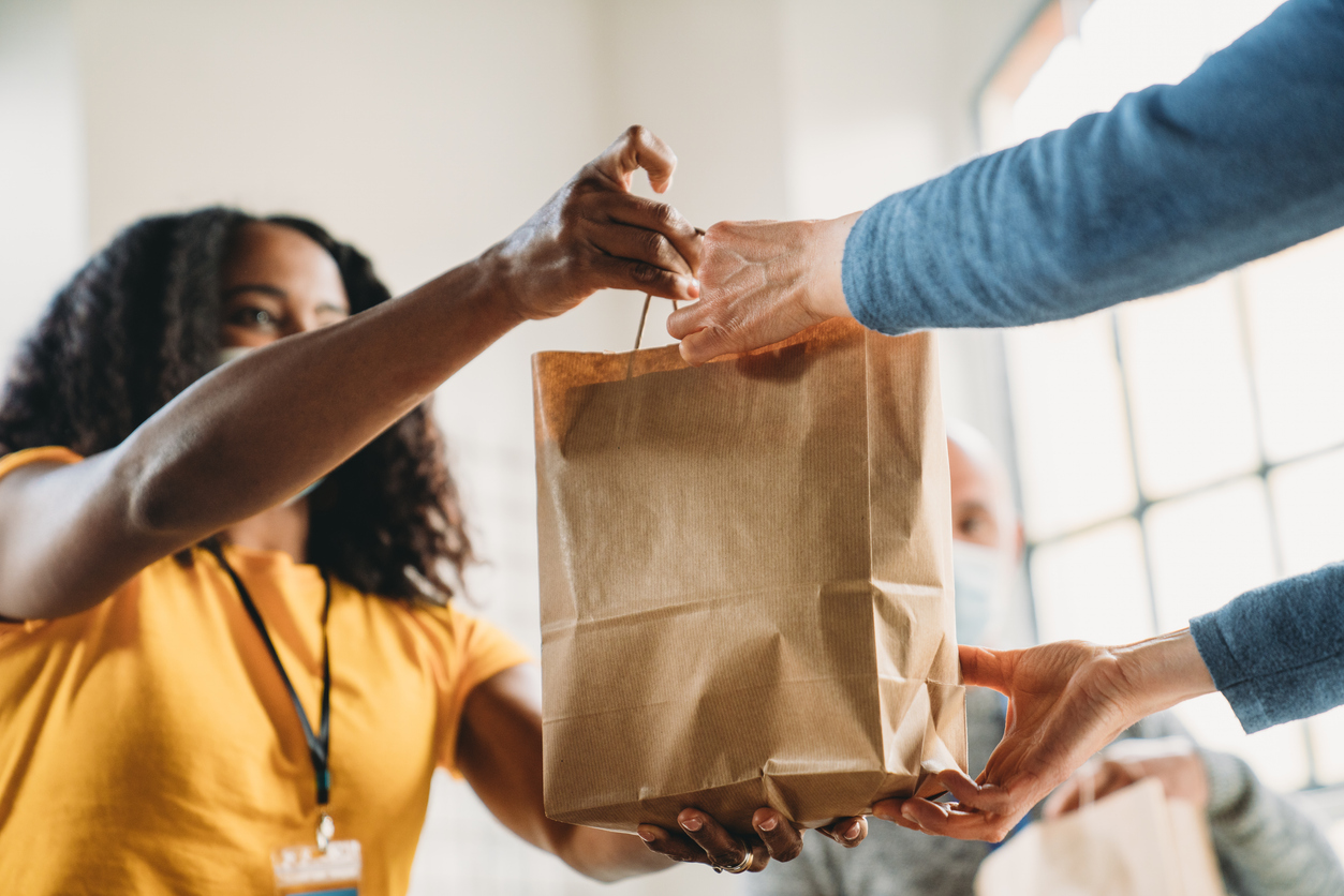 A woman taking a paper bag of food