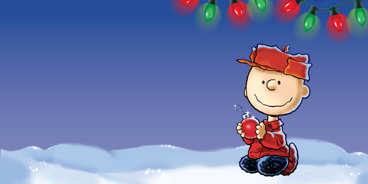 Charlie Brown with Christmas lights over him as he walks through snow