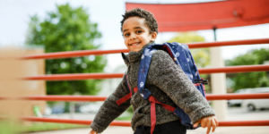 A young boy smiling as he ventures onto Hope Academy's campus for his first day in the school