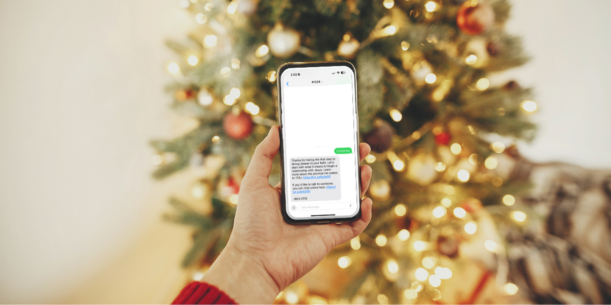 Someone texting CHRISTMAS to 41224 in front of a Christmas tree